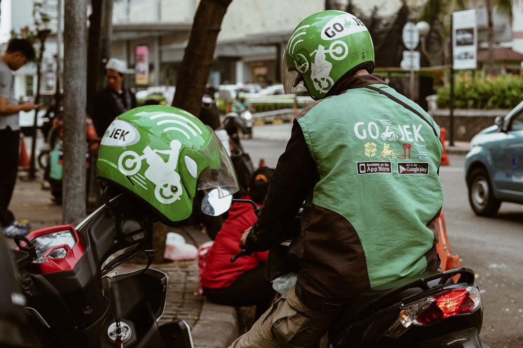Εργαζόμενοι στην εταιρεία Gojek φορόντας γιλέκα και κράνοι με την επωνυμία της εταιρείας