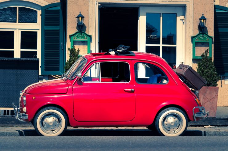 ένα κοκκινο fiat στους δρόμους της ιταλίας με βαλίτσα στο πίσω μέρος του