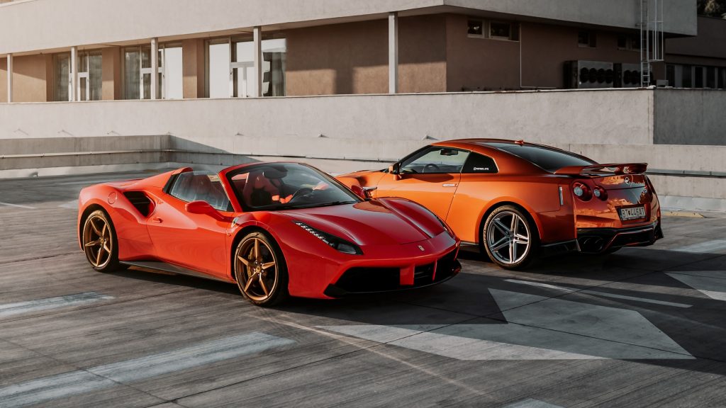 2 σπορ αυτοκίνητα σε χρώμα πορτοκαλί και κόκκινο παρκαρισμένα αντικριστά 