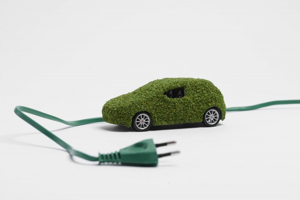 οικολογική ηλεκτρική μινιατούρα αυτοκινήτου με άσπρο background και ντυμένο με πράσινο φύλλωμα