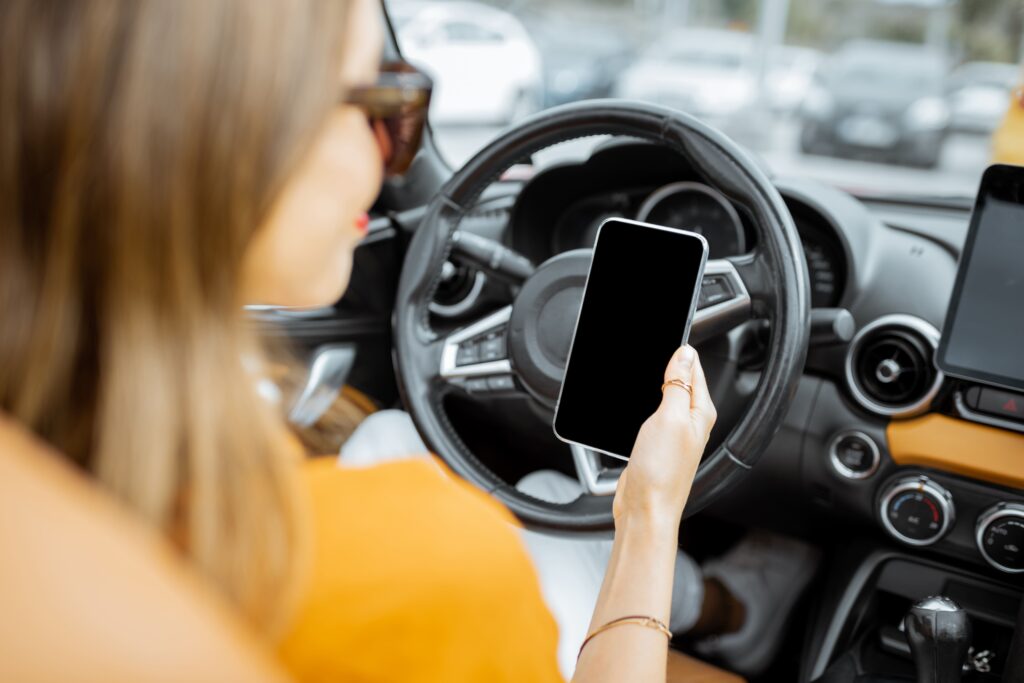 γυναίκα χρησιμοποιεί το κινητό της ενώ οδηγεί