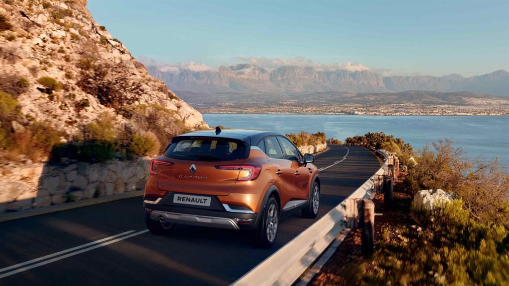Το Renault Captur σε πορτοκαλί χρώμα εν κινήσει σε δρόμο με φόντο τη θάλασσα