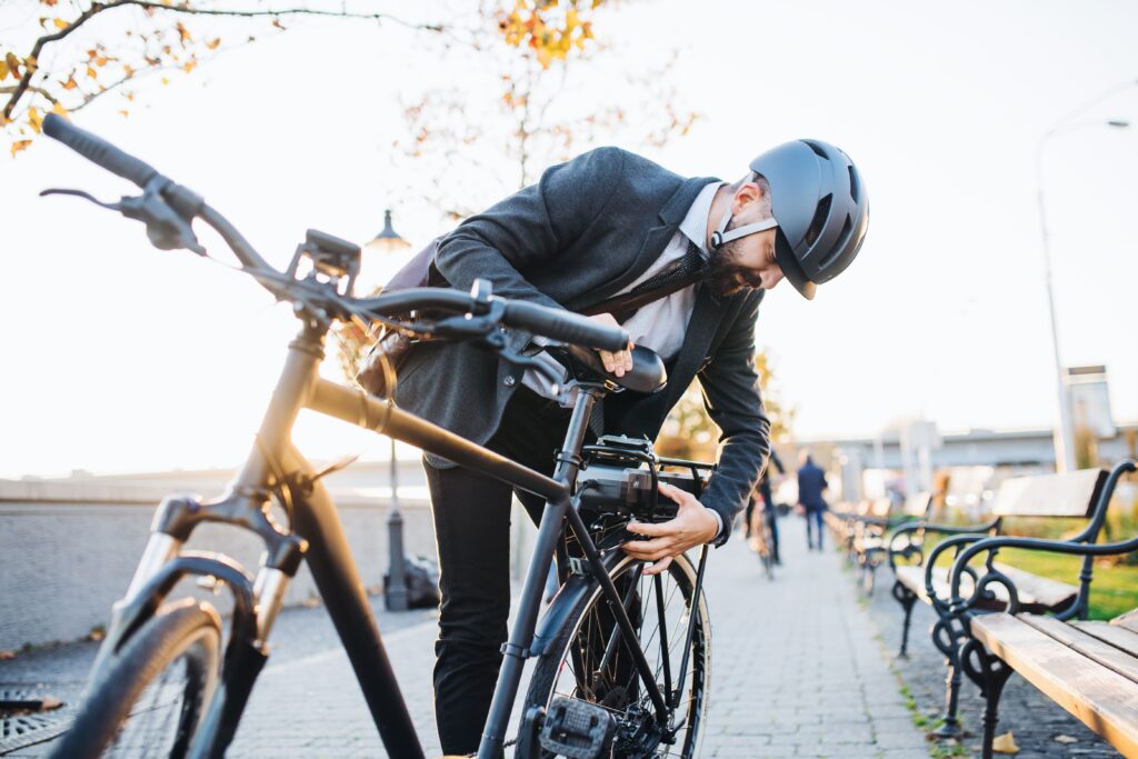 Άντρας επιχειρηματίας τοποθετεί τη μπαταρία στο ηλεκτρικό του ποδήλατο ώστε να μεταβεί στη δουλειά του